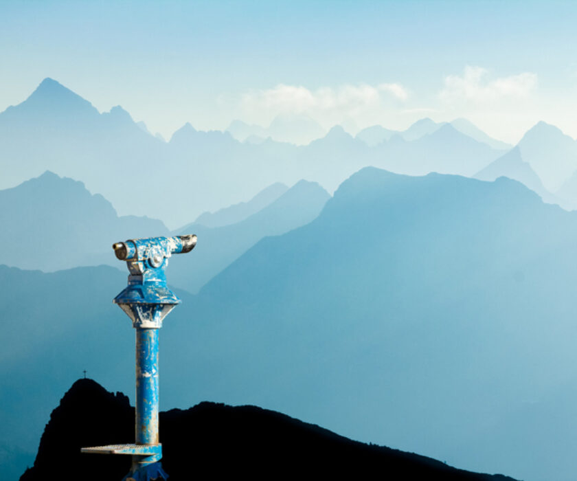 Public binoculars and Mountain Silhouettes at Sunrise. Foresight and vision for new business concepts and creative ideas. Alps, Allgau, Bavaria, Germany.